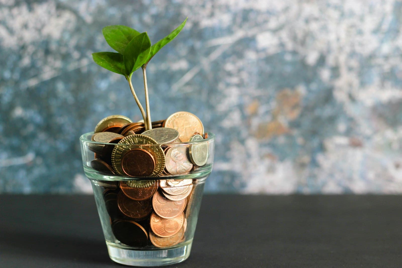 Person putting coins into a savings jar representing monthly savings goal calculation
